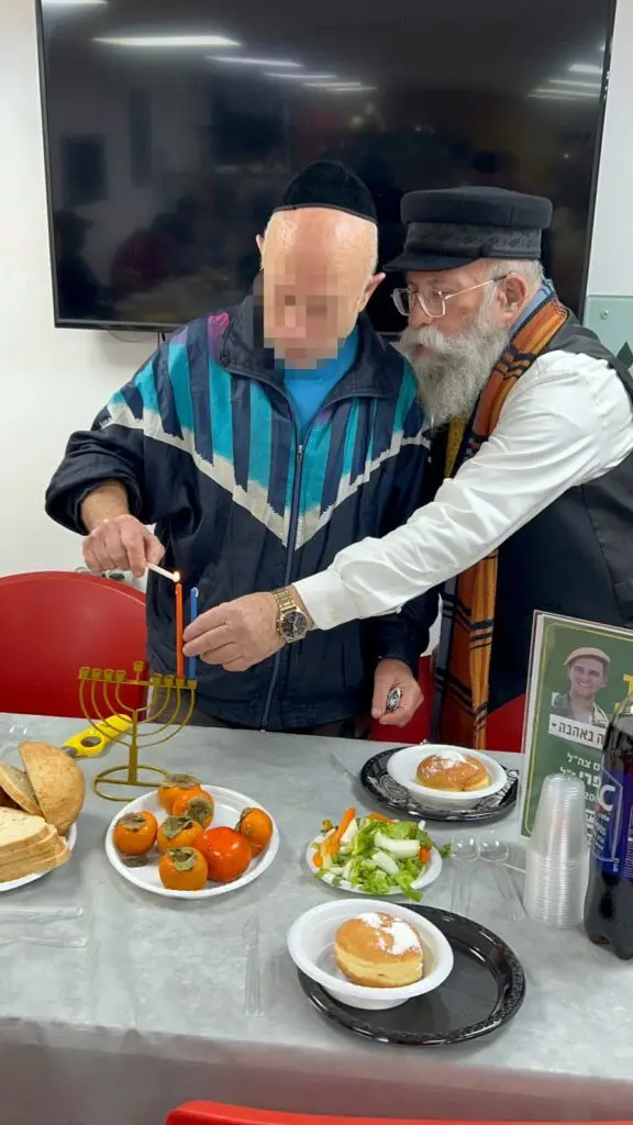 ניצול שואה מדליק נרות חנוכה במסיבה חגיגית שנערכה עבור קשישים ונזקקים